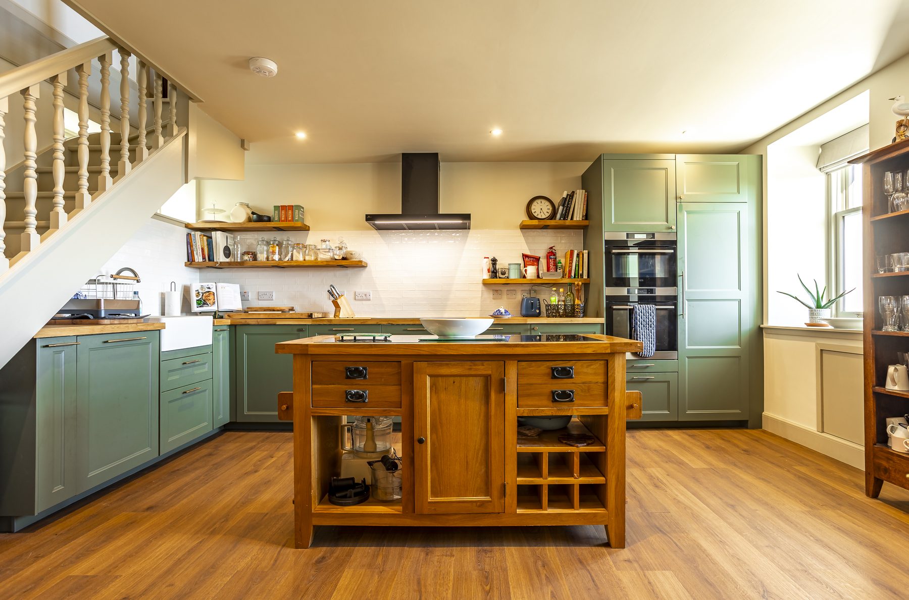 Sage-green kitchen with oak island